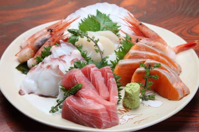 白い皿に美しく盛り付けられた新鮮な刺身の盛り合わせ、和食の盛り付けの極意で格調高い食卓を演出