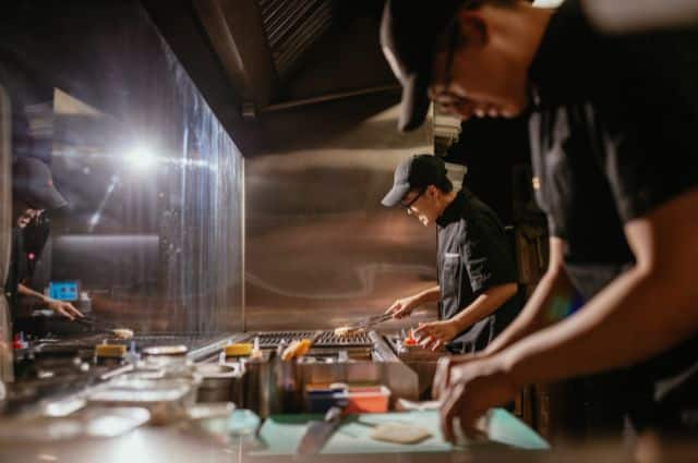 忙しい厨房で料理を作る飲食店スタッフ、業務効率化による人手不足解消の必要性